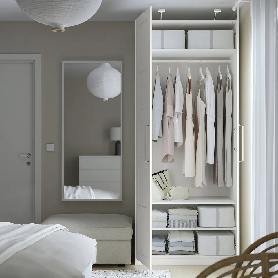 Modern bedroom with PAX wardrobe and mirror, offering neat storage.