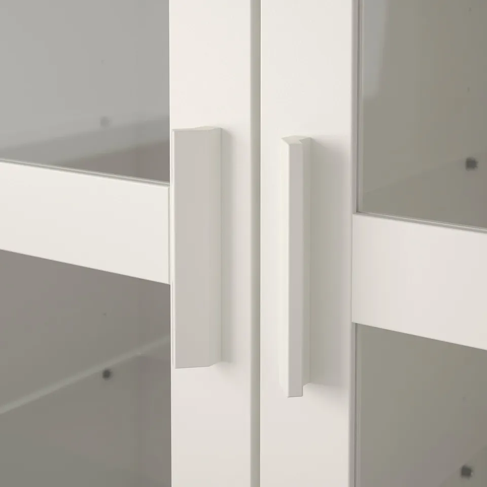 Close-up of sleek, white cabinet handles. Smooth finish suggests quality construction, part of modern furniture set.