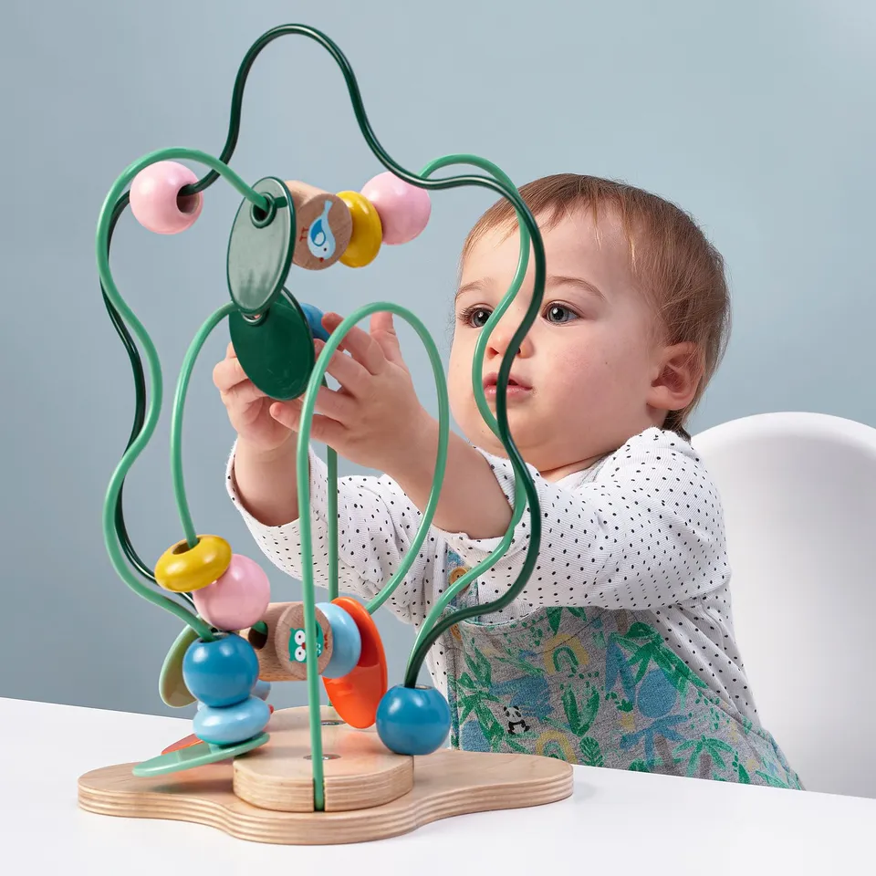 Baby plays with colourful bead maze toy; learns shapes, colours, and motor skills.