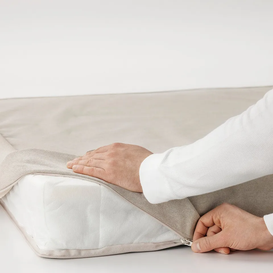 Persons hands removing mattress cover, showcasing zip access for easy cleaning.