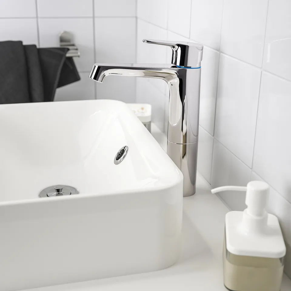 Modern BROGRUND tap beside white sink with soap dispenser & mirror in bright, tiled bathroom.