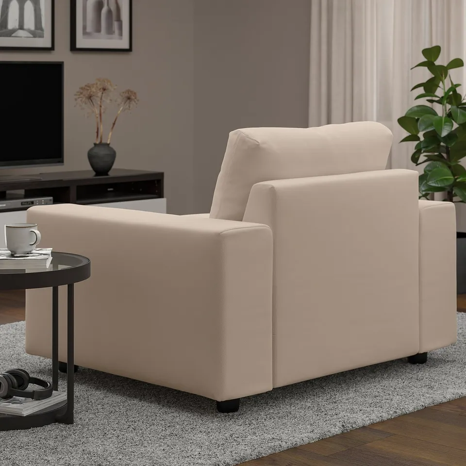 Light living room with beige VIMLE armchair, dark side table, coffee mug, and plant.