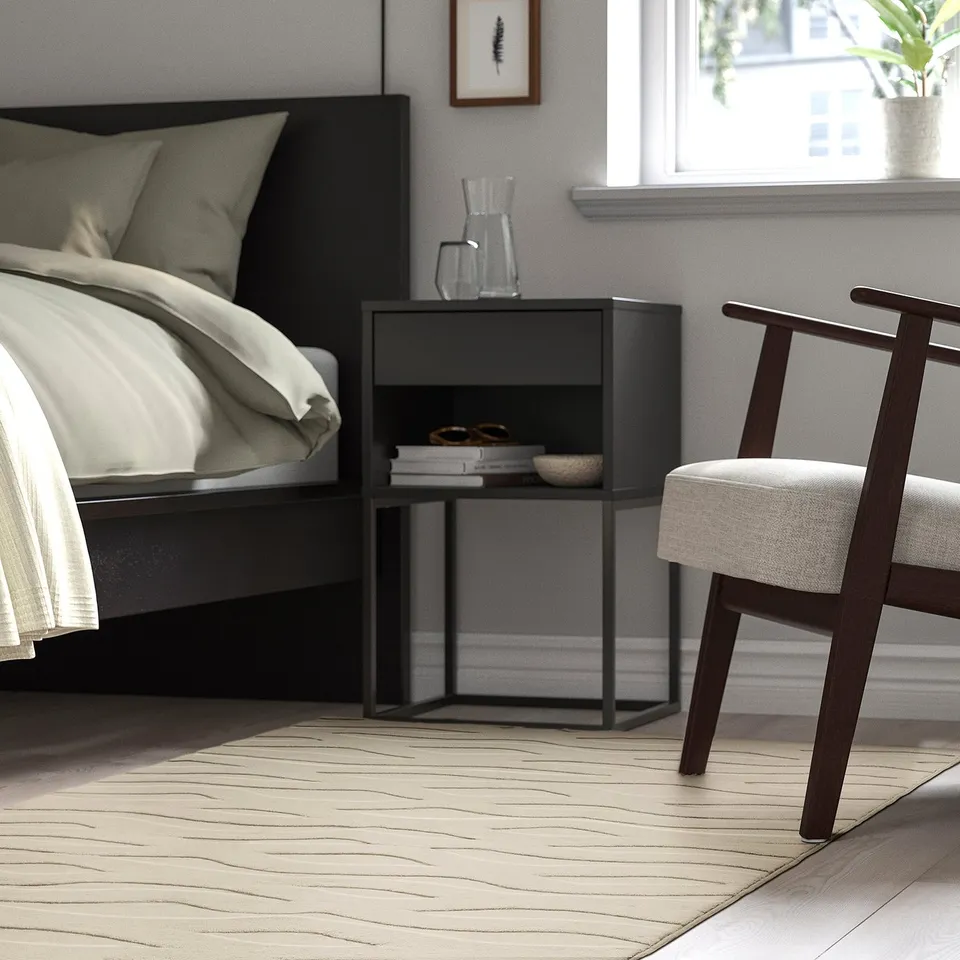 Modern bedroom with black VÄXELFEL rug, beige, rectangular, soft & thick, under bed & chair.