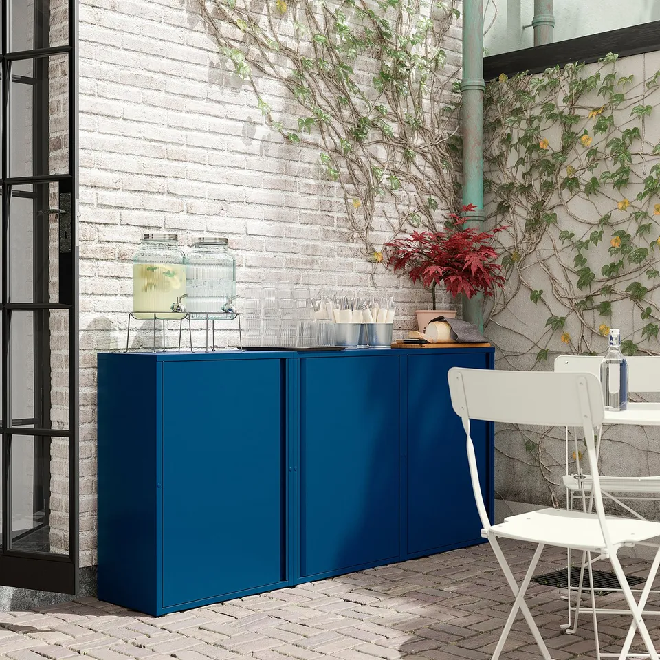 Blue SUNDSÖ storage cabinet on brick patio with white chair.