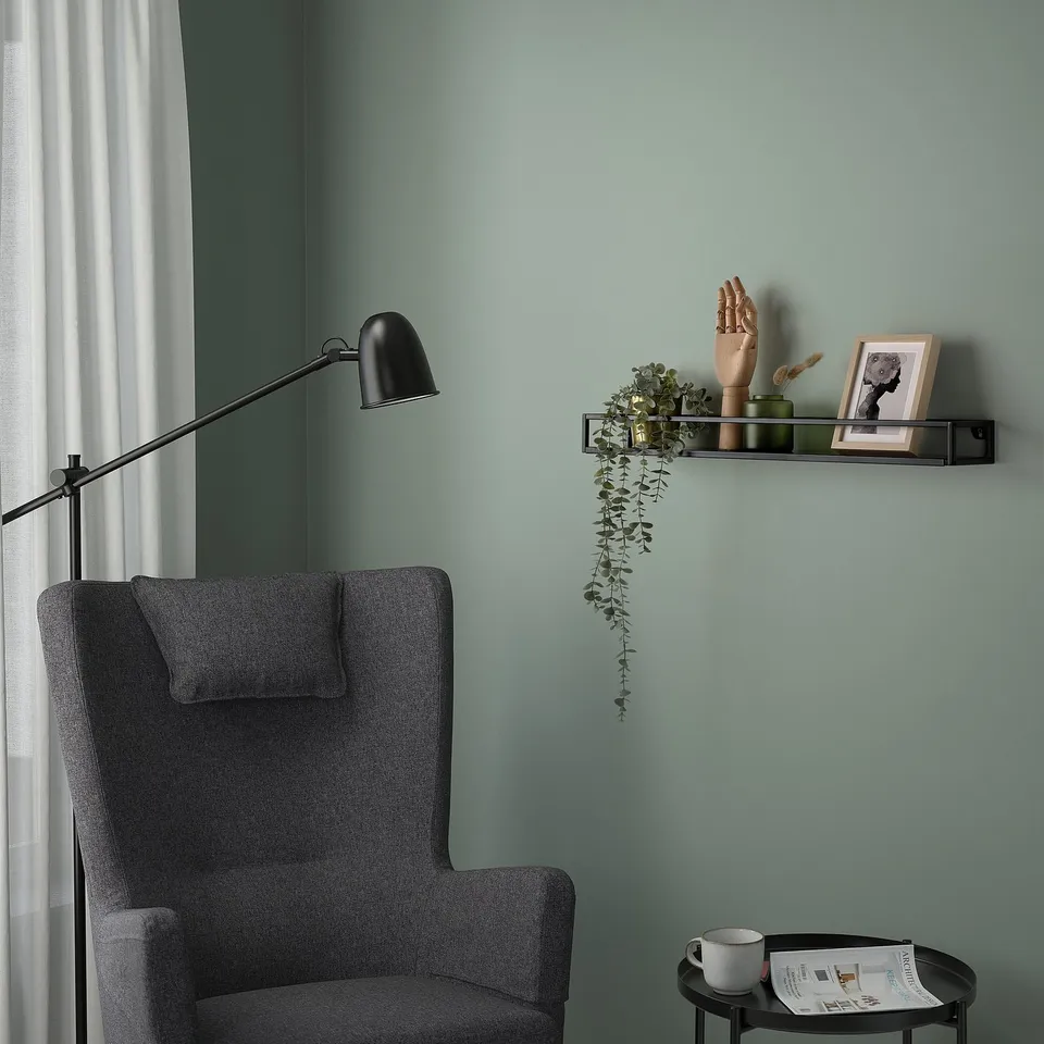 Small modern grey LINDÅSEN shelf holds plants, decor, and photo near large comfy chair, black lamp, and small table with cup and magazine.
