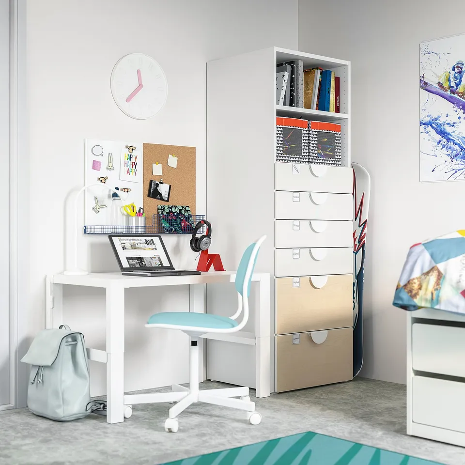 Teenage study space with white SMÅSTAD desk, light blue chair, storage unit, wall clock, and backpack. Includes laptop, headphones, and supplies.