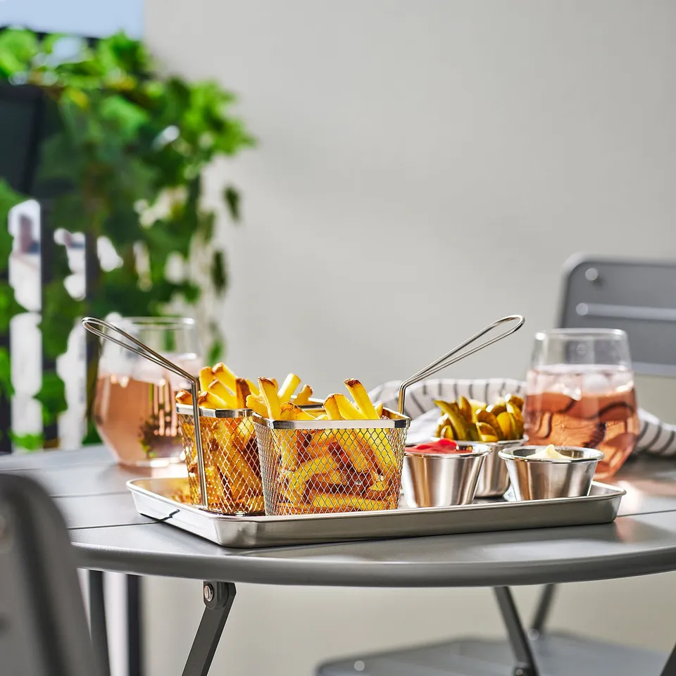 Outdoor table with GRILLTIDER fry basket and glasses, stainless steel.