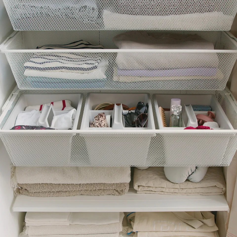 Organised drawer with FÅNGGRÖDA insert in white mesh basket, holding folded clothes, accessories, and small items.