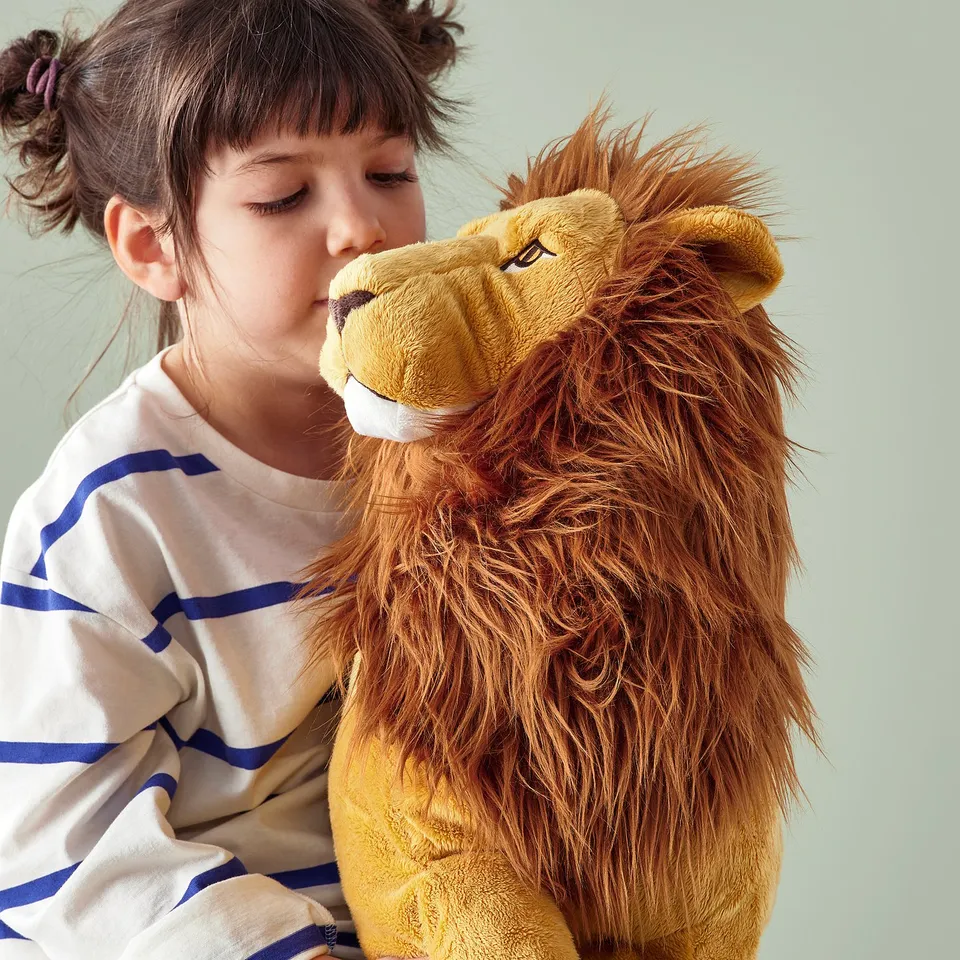 Young girl hugging large plush lion teddy, both comforting each other.