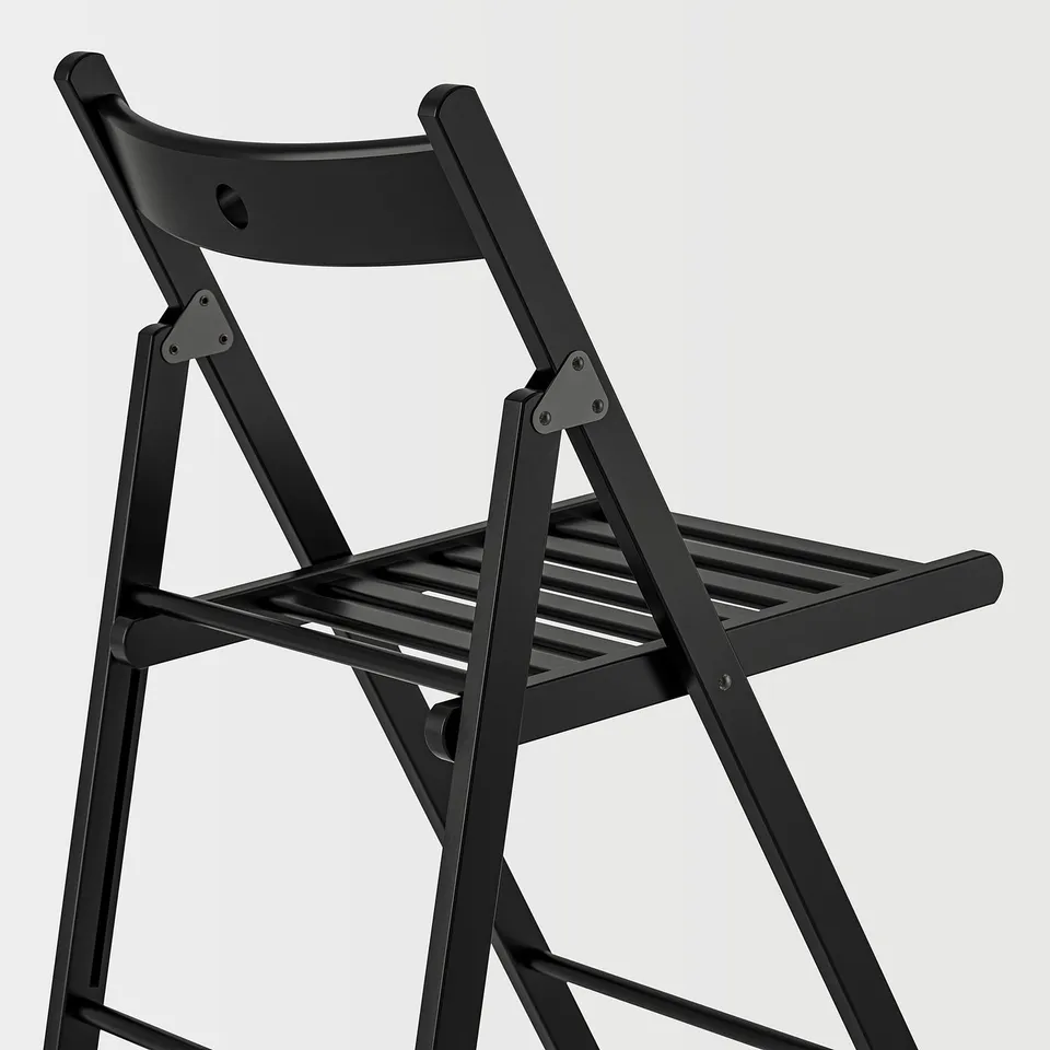 Black folding chair with slatted seat, shown partially folded. Sturdy wooden back and legs with metal hinges. Compact design for easy storage.