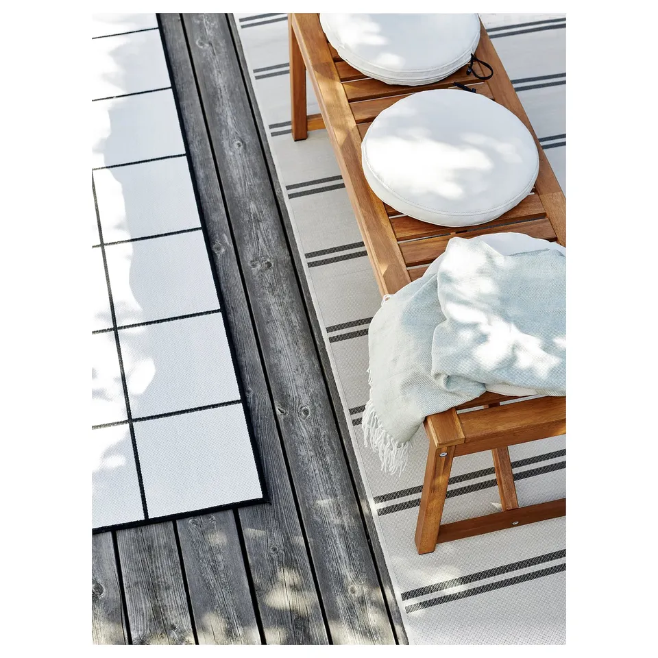 Wooden patio chairs with white cushions and blanket. Simple, modern design. Perfect for outdoor relaxation.