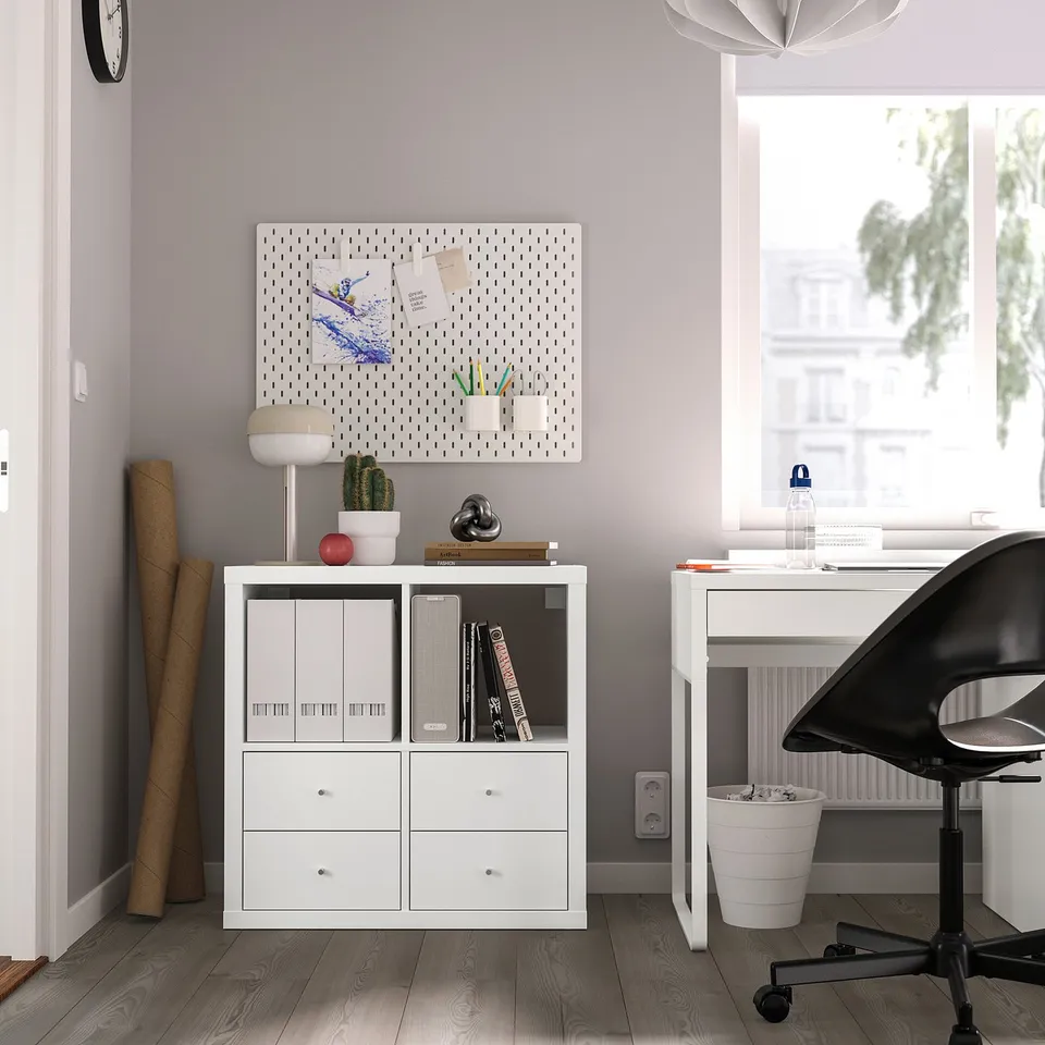 Modern home office with KALLAX shelf, books, decor, chair, desk, window.