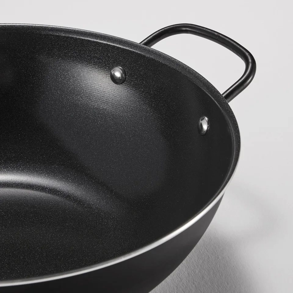 Black wok with non-stick coating and sturdy handles, perfect for cooking healthy meals.