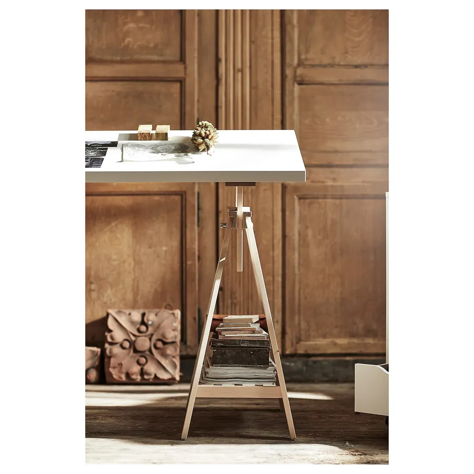 A sleek, modern white desk with a metallic trestle, featuring a minimalist design. The tabletop sits atop a sturdy, slim frame with built-in shelves.