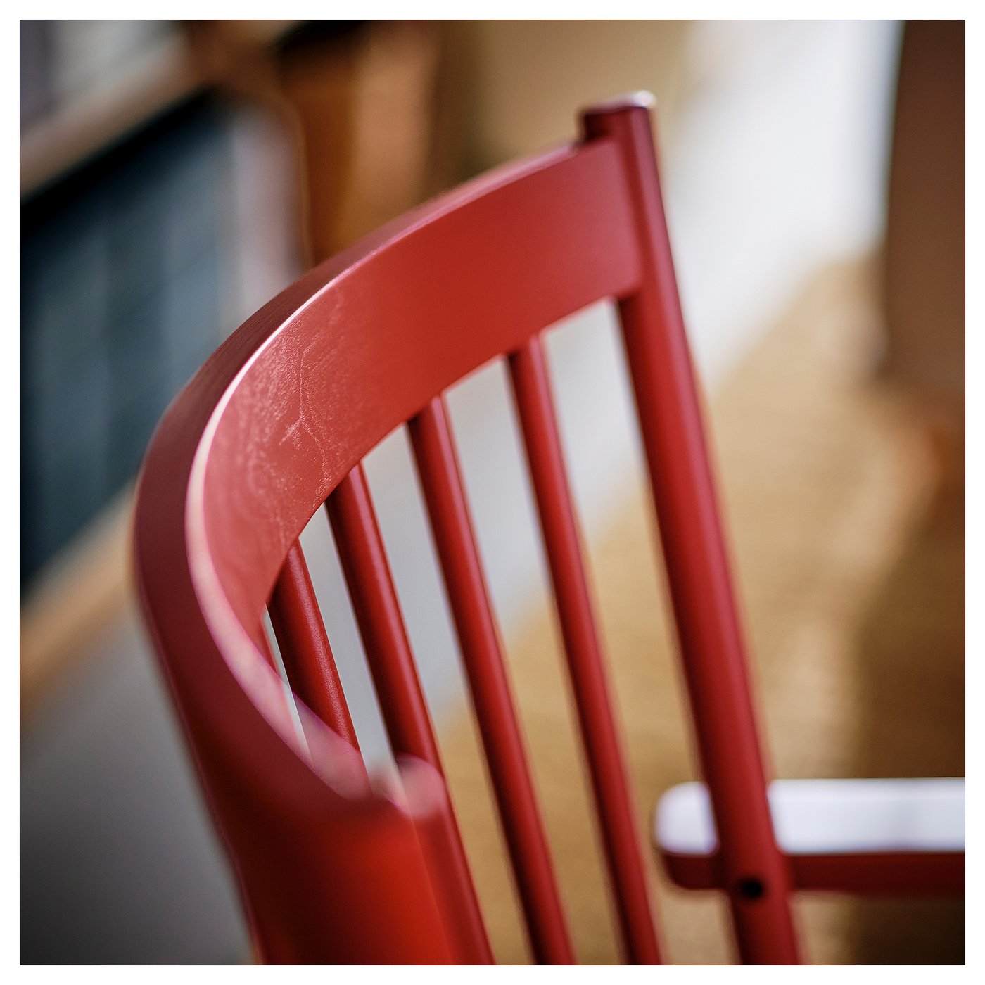 Red wooden chair backrest, smooth finish, elegant curved armrest detail.