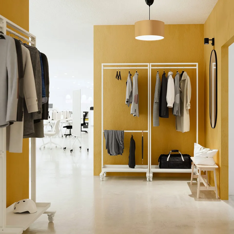 MITTZON frame in yellow, steel with epoxy, holds clothes & gear. White pendant light, mirror, stool beside.