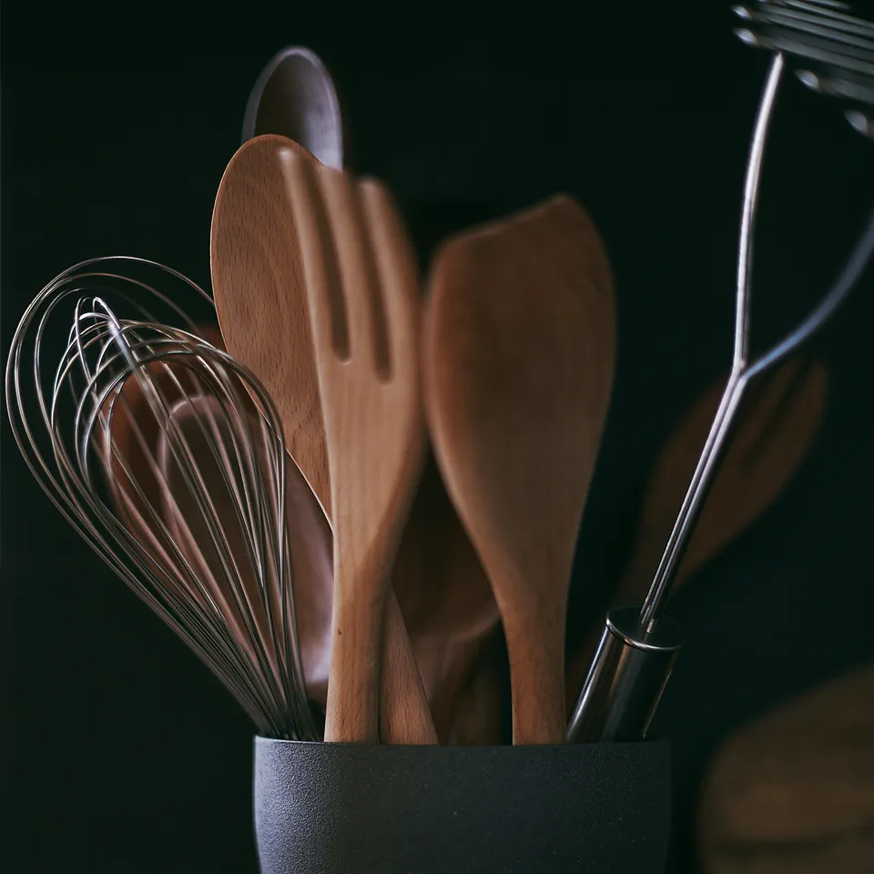 Black RÖRT utensil holder with wooden tools. Round shape, dark hue, beech wood material.