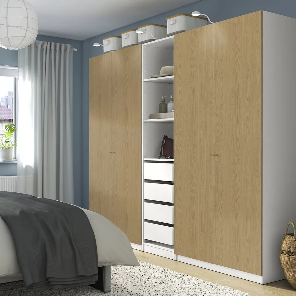 A spacious PAX wardrobe in light wood hue. Tall and wide, it fits well in a bedroom setting. It includes drawers and shelves for storage.