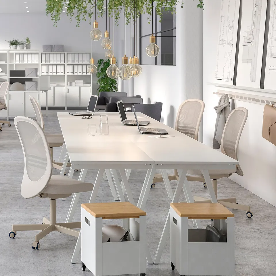 Minimalist office with TROTTEN desk, laptop, chairs, plants, bright windows.