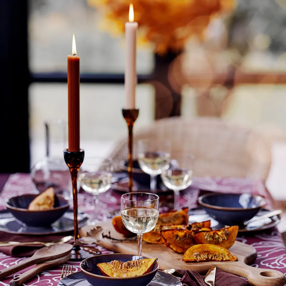 Brown glass candlesticks on autumn table, with dried leaves and plates.