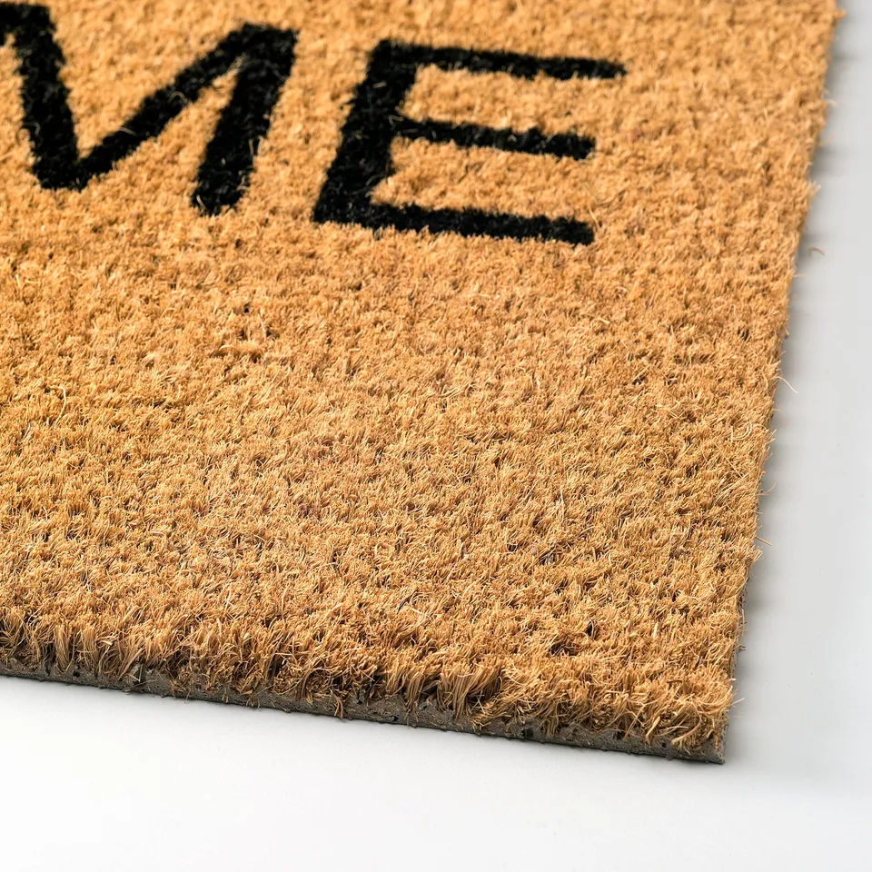 Doormat with bold welcome text, made of durable coir fibres, natural latex backing, placed on a flat surface.
