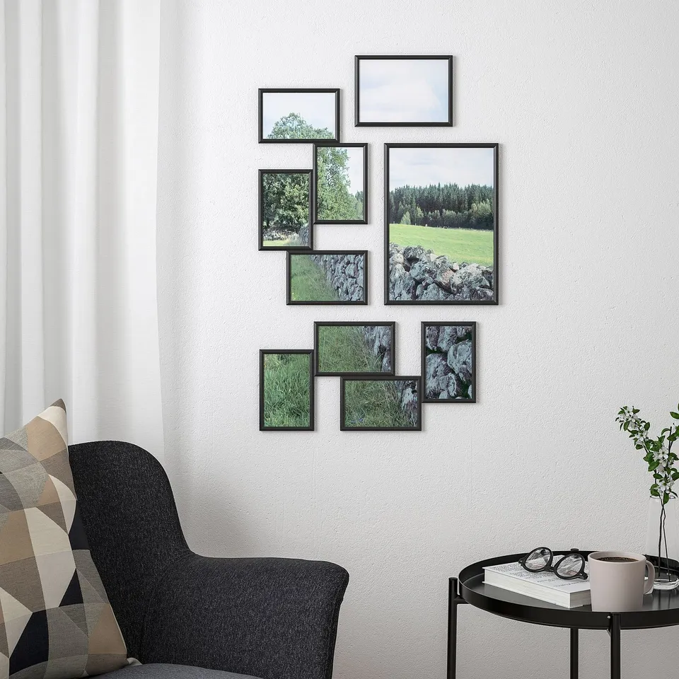 Modern living room with YLLEVAD frame collage above black chair. Unique black frames showcase landscapes on a white wall, enhancing decor.