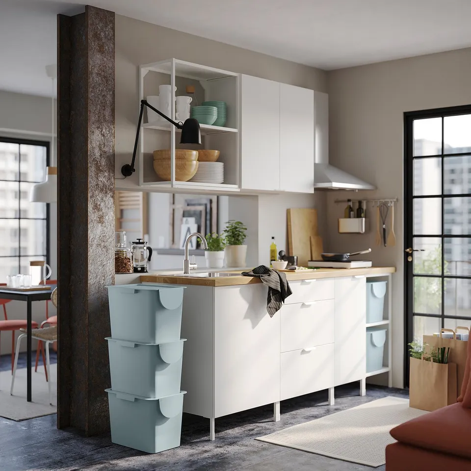 Modern kitchen with white cabinets and TRÖSKNING bins. Recycled plastic, fits under cabinets.