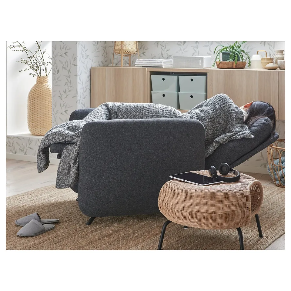 Modern living room: grey EKOLSUND recliner, woven ottoman, wood cabinet, cosy decor.
