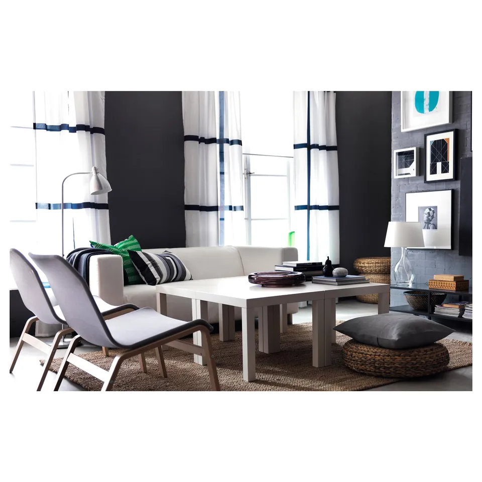 Modern living room with white sofa, light grey chairs, LERSTA adjustable floor lamp, woven basket, and framed art on wall.