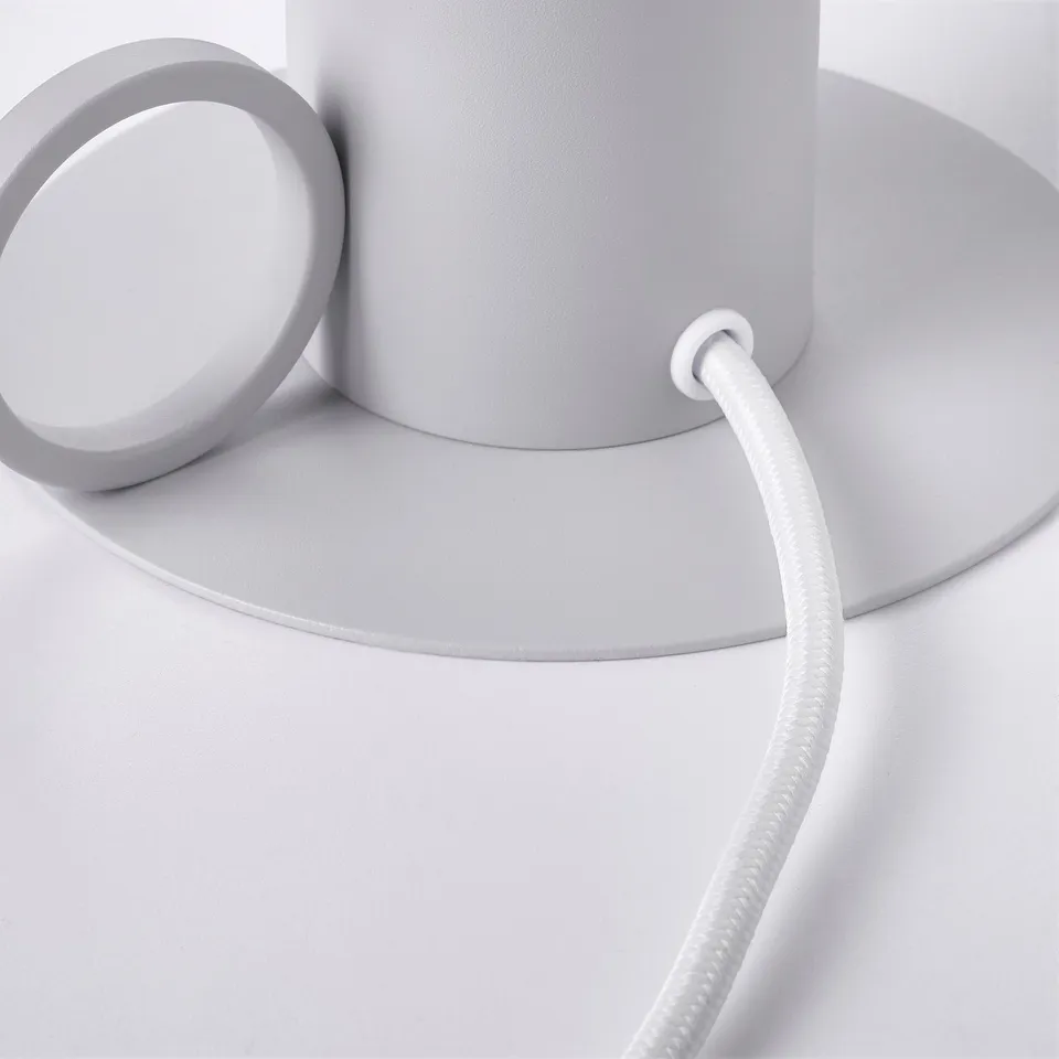 Modern lamp with textured surface, flexible cord, and sleek design, standing on a flat surface.
