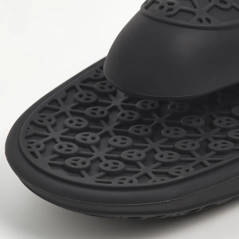 Black silicone trivet with intricate hole patterns for oven-safe use.