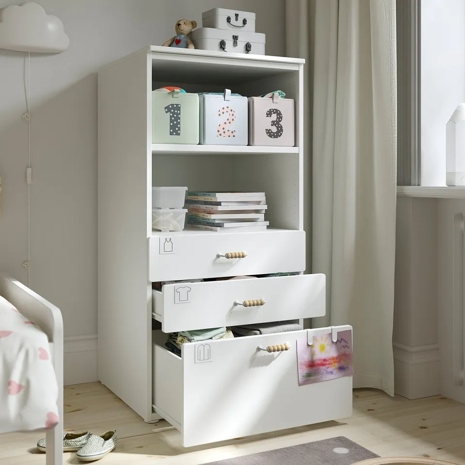 White childrens bookcase with labelled boxes and open drawers in bedroom.
