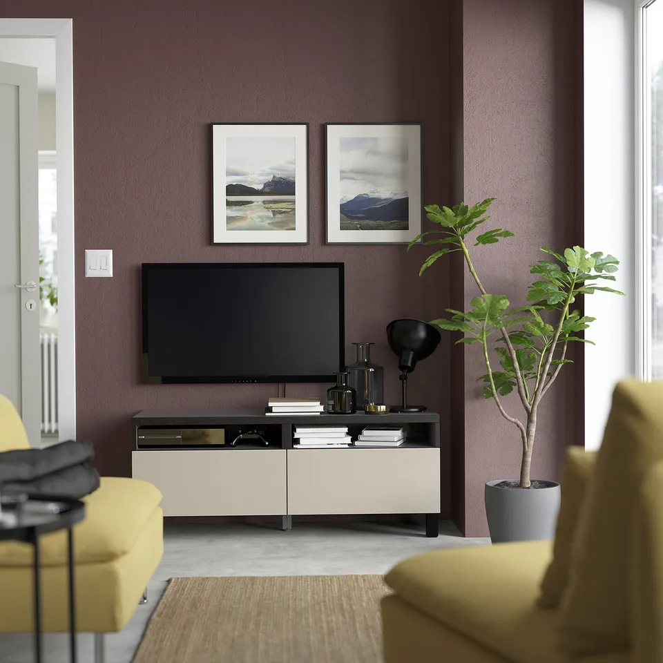 Modern living room with BESTÅ tv stand, yellow chairs, and green plant, against purple walls with mountain art.