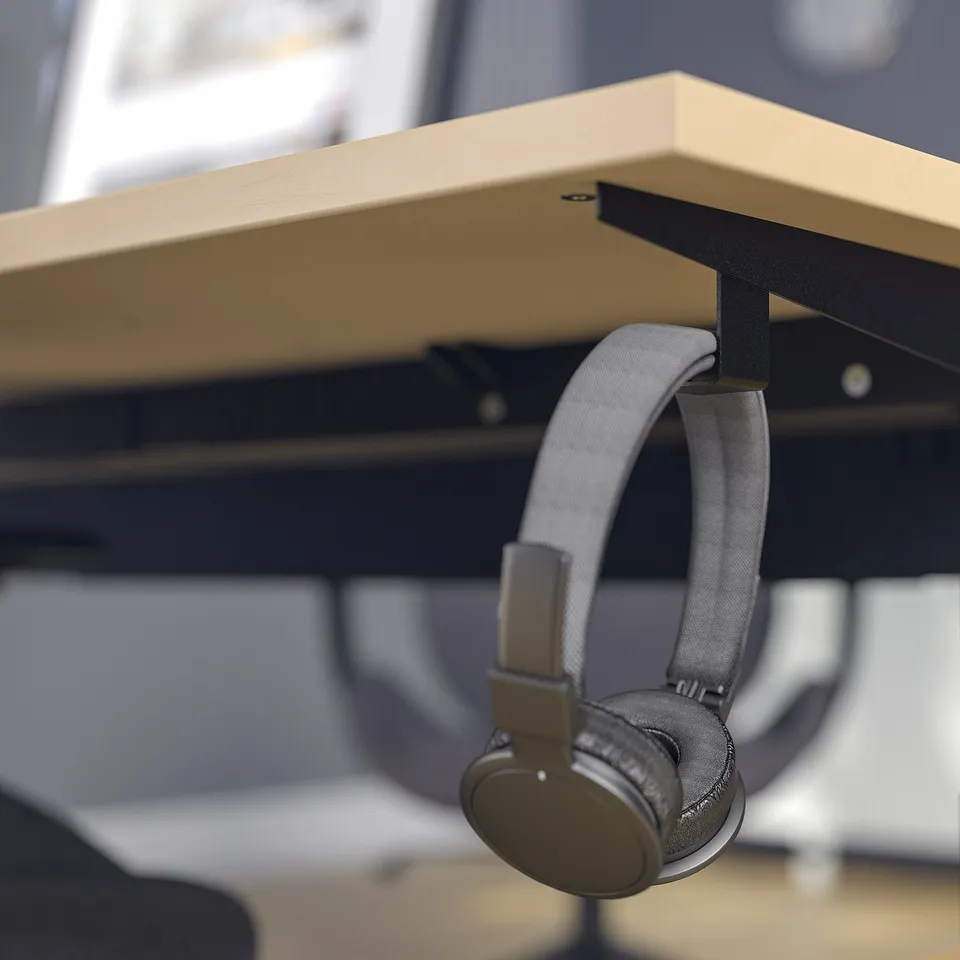 Black headphones hang from a desk hook.