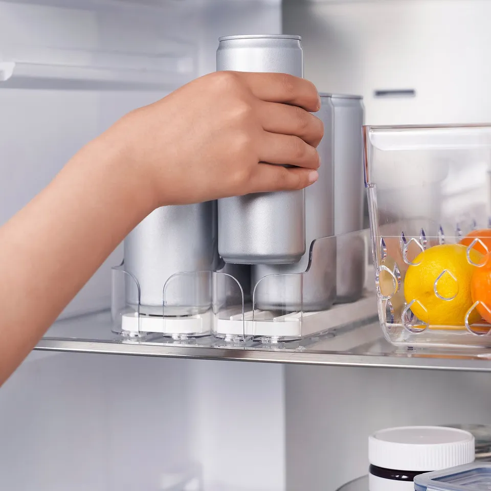 Hand holding can in fridge organiser with adjustable compartments.