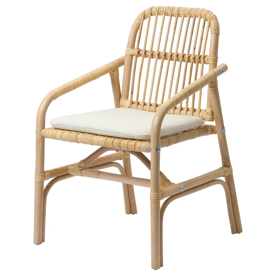 A SALNÖ chair, crafted from light beige rattan with a woven design. It armrests and a removable cushion for comfort.