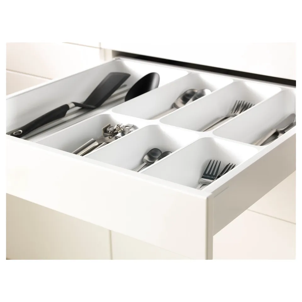 White kitchen drawer organiser with compartments holding utensils and cutlery, part of the METOD system.
