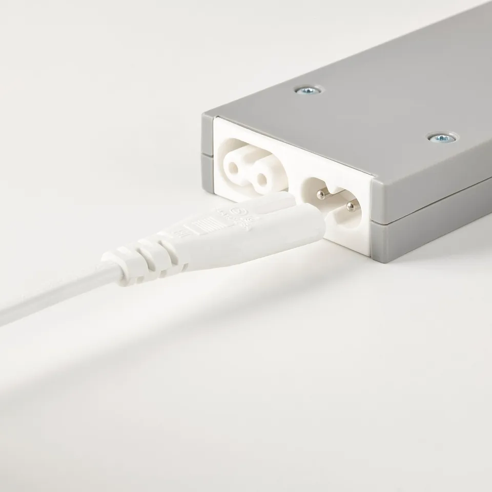 Silver power adapter with white cord plugged in, designed for use with IKEAs trådfri wireless dimmer system.