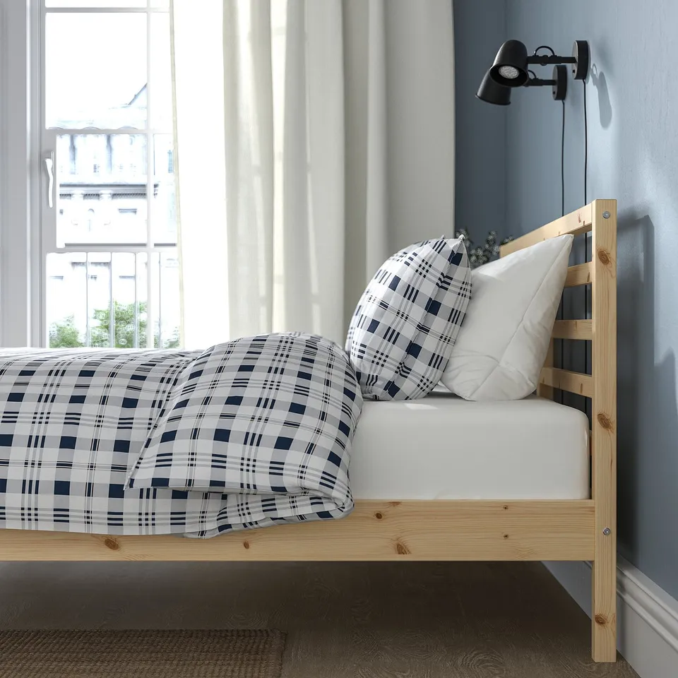 Cosy bedroom with blue and white chequered bedding on a wooden TARVA bed frame near a large window.