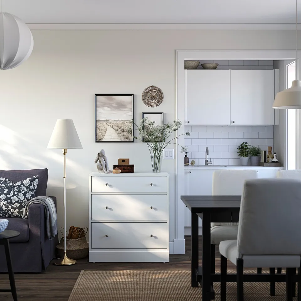 Modern living room with white HAVSTA drawers, sofa, and dining table. Decorated with art and vase.