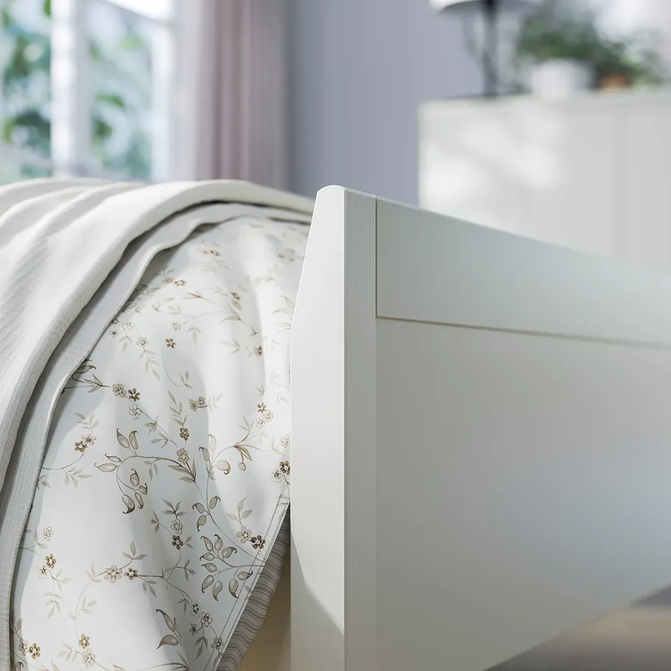A light blue IDANÄS bed frame with a floral-patterned mattress, set near a window.
