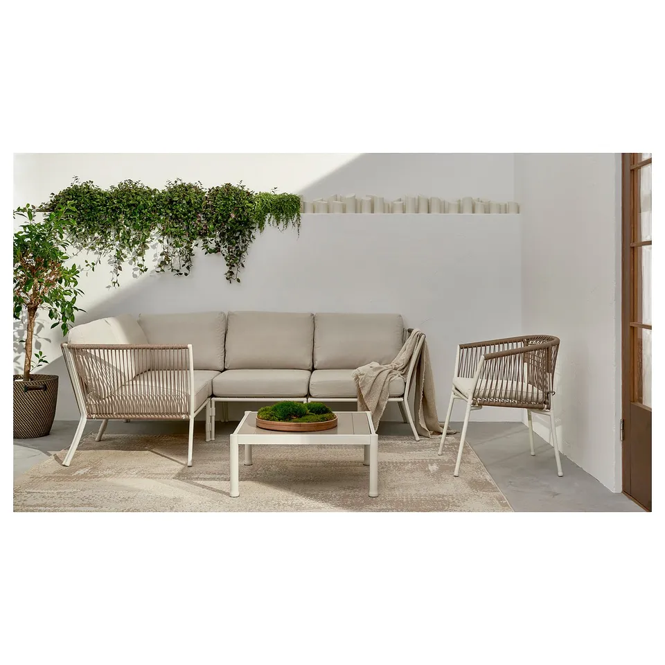 A modern outdoor lounge set with a beige sofa and white wicker chairs, perfect for relaxing on a patio.