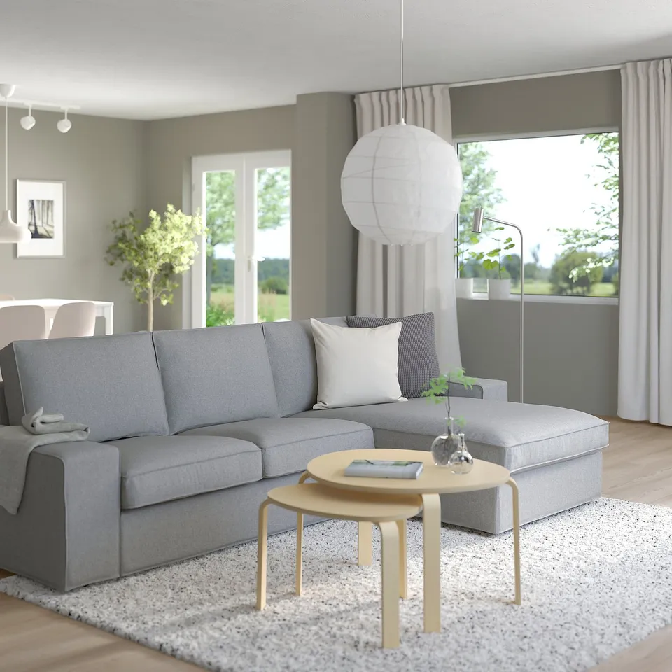 Modern living room with KIVIK sofa, table, lamp, plant, and tree view.