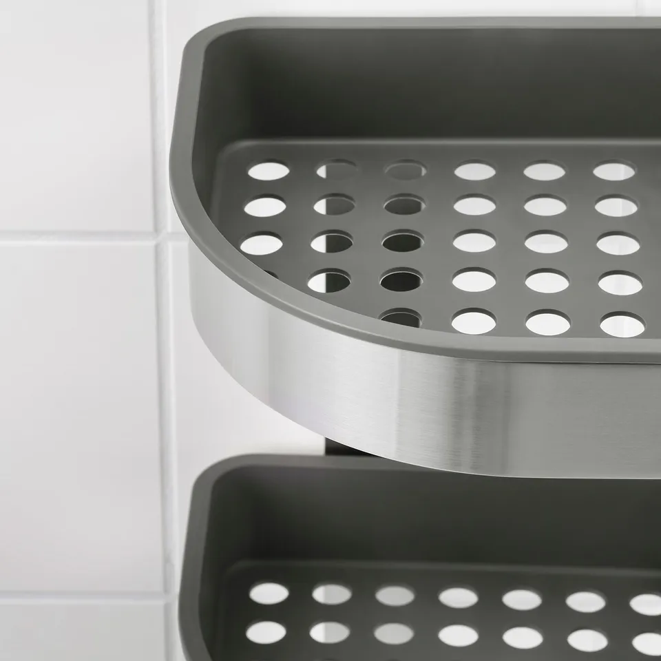 Modern stainless steel and black plastic storage shelves with drainage holes against a tiled wall.
