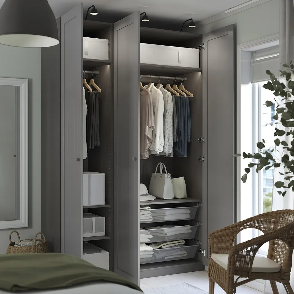 Modern closet with open door, clothes, storage, led lights. White tiles, wicker chair, green blanket, large mirror.