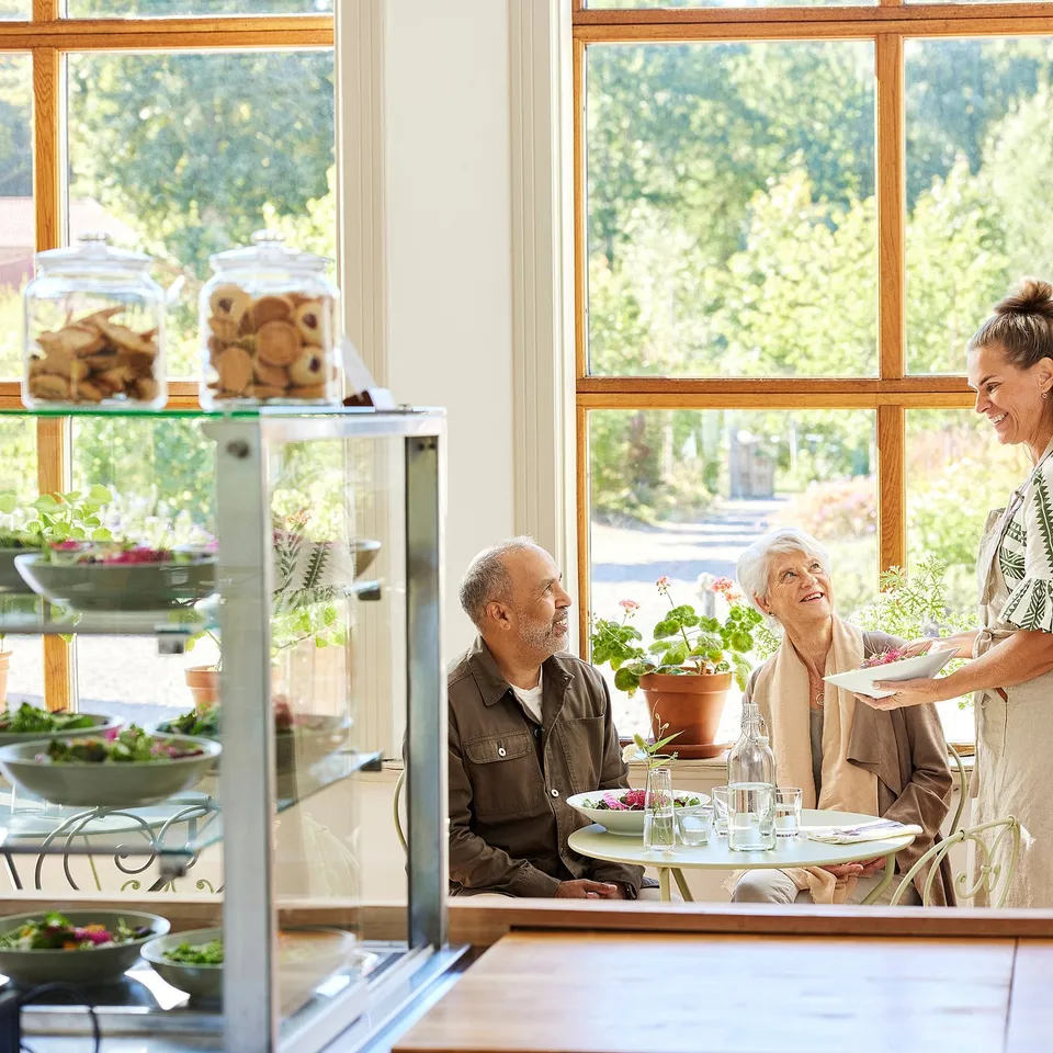 Elderly couple smiles at café, sharing meal and cookies.