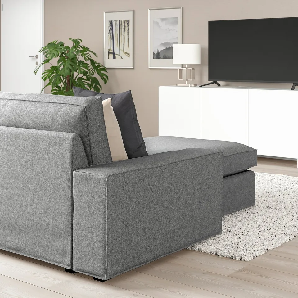 Cosy KIVIK grey sofa with cushions, large flat screen tv, white cabinet, rug, and plant. Sofas size notable compared to other items.