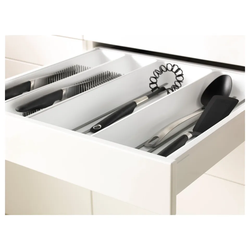 White kitchen drawer, organised with knife rack, whisk, spatula, and serving spoon, designed for easy access and cleanliness.