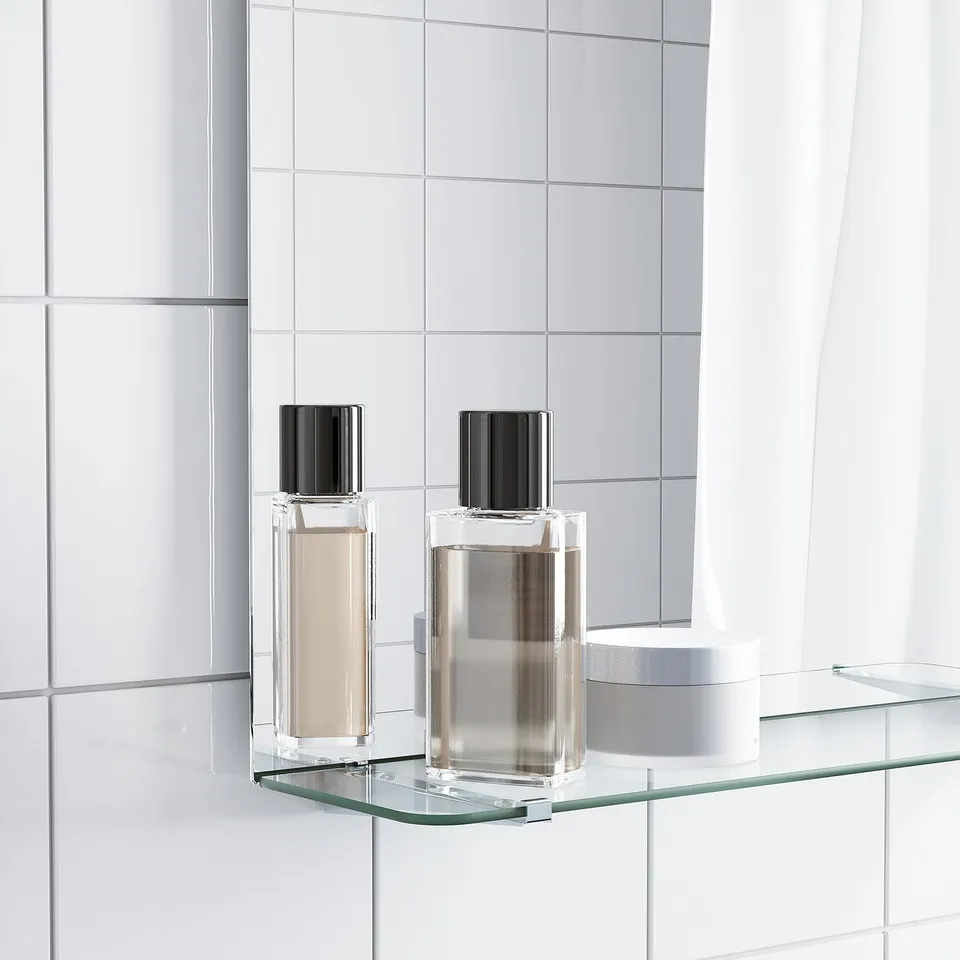 Clear glass shelf mirror with two perfumes.