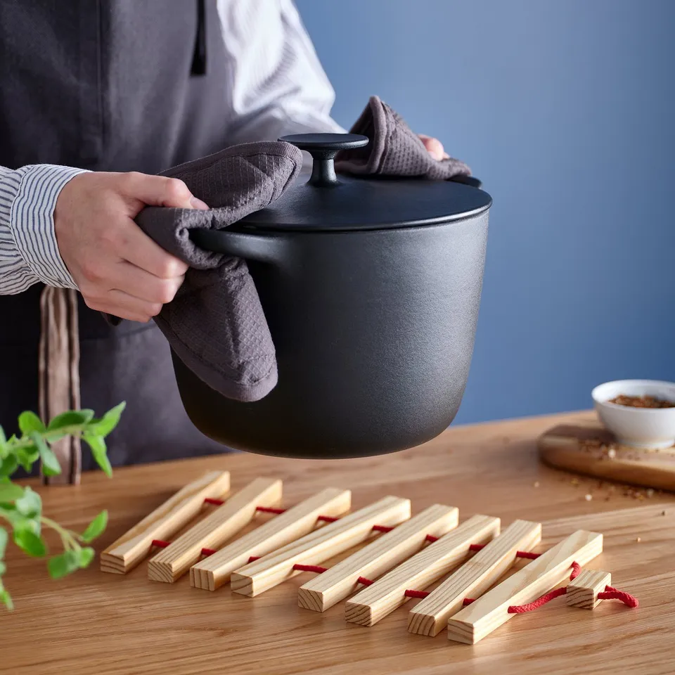 Person mixing herbs and food on wooden table.